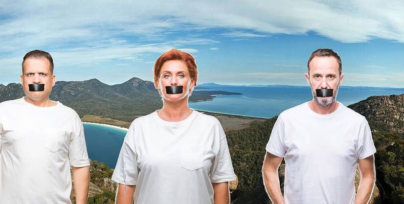 People standing in front of Wine Glass Bay lookout with tape covering their mouth